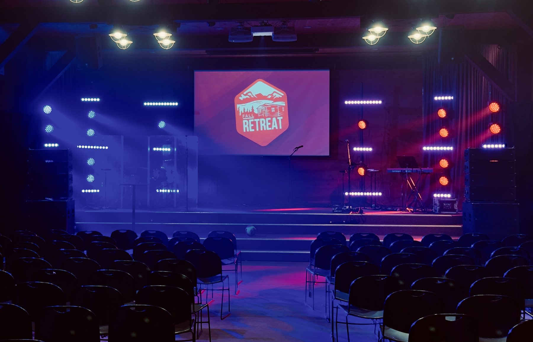 Wide view of the empty auditorium in preset lighting with the Fall Retreat logo on screen