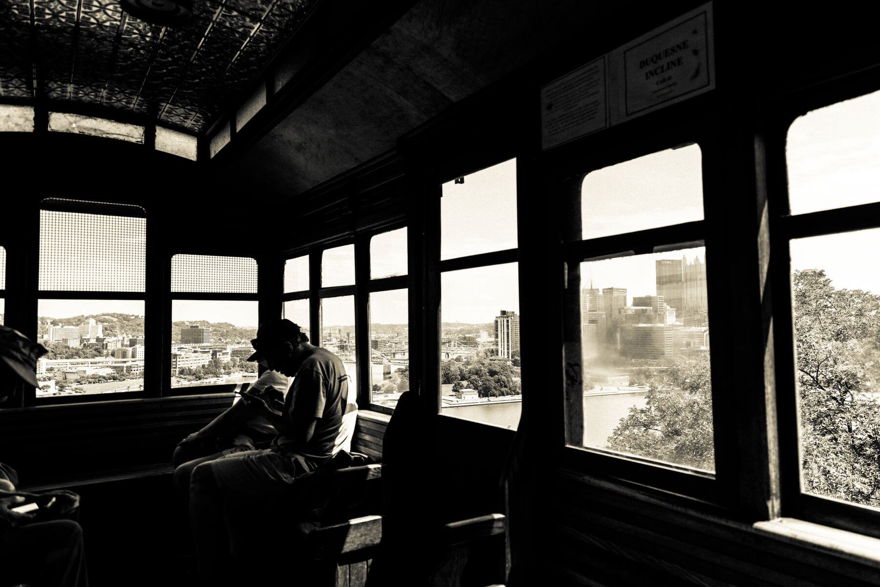 A rider silhouetted inside a Duquesne Incline car overlooking Pittsburgh
