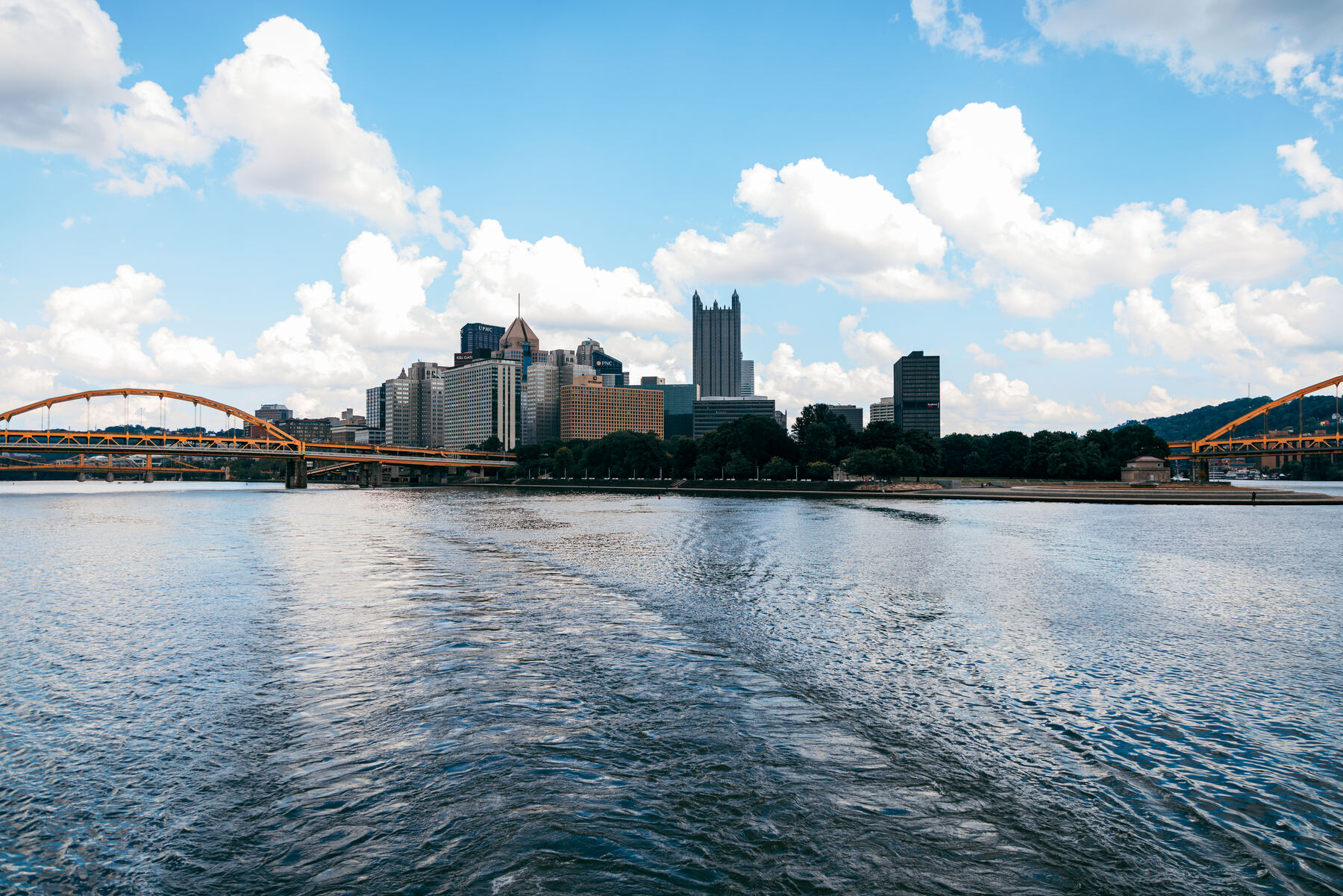 Pittsburgh's yellow bridge on the left of frame, downtown skyline reflected on the river